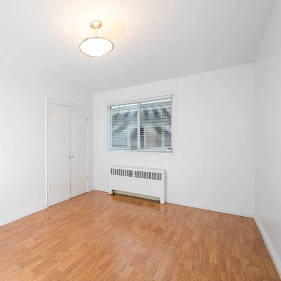 a room with a wooden floor and a window with blinds.