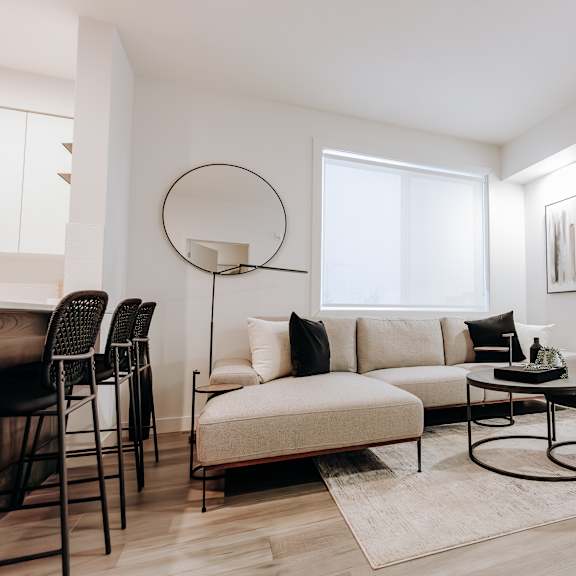 a modern living room with a white sofa, a black table, and a large window.
