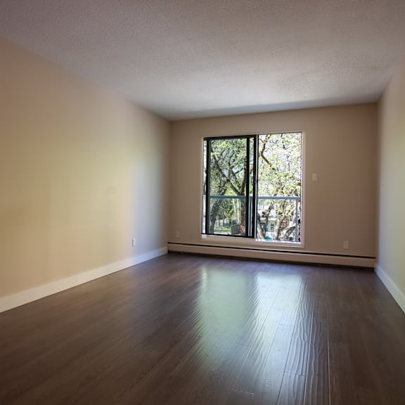 empty room with a window and wooden floor.