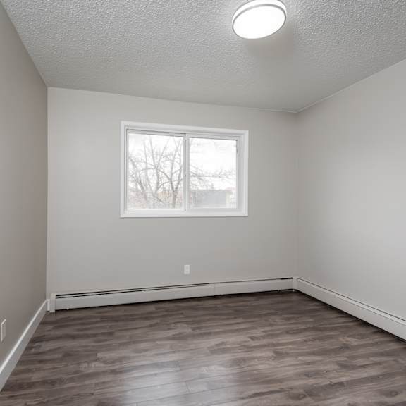 a room with a window and wooden flooring.
