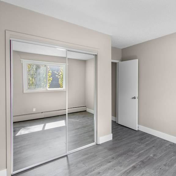 a room with a white door and a window with a reflection of trees.
