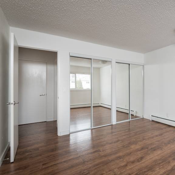 a room with white walls and wooden floors with a sliding glass door.
