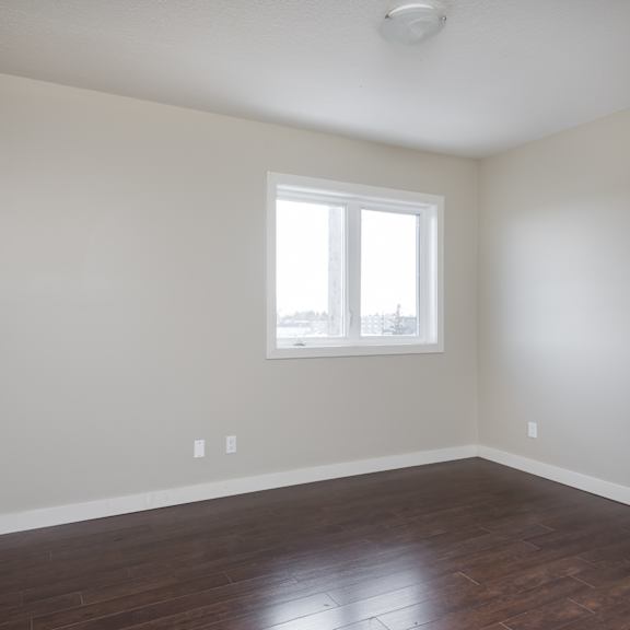 a room with a window and wooden floors.