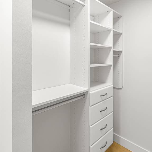 a white shelving unit with drawers is in a room with white walls.