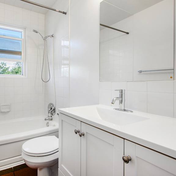 a white bathroom with a toilet, sink, and bathtub.