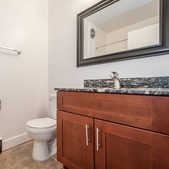 a bathroom with a toilet, sink, and a mirror.