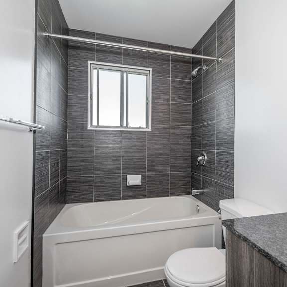 a modern bathroom with a white tub, toilet, and sink.