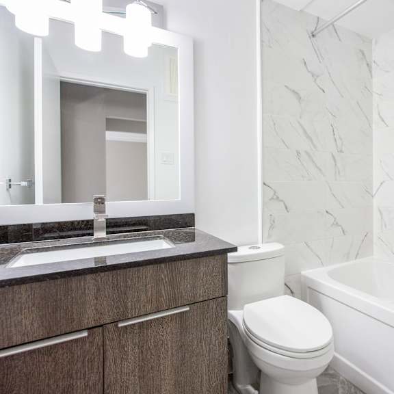 a white bathroom with a marble wall and a white toilet.