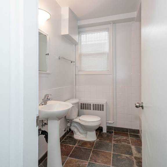 a white bathroom with a toilet, sink, and window.