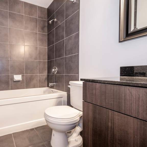 a white toilet sits next to a bathtub in a bathroom with brown tiles.