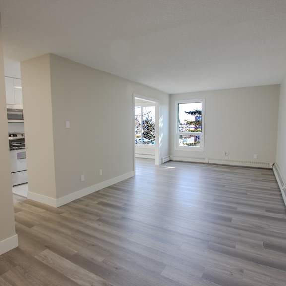 a spacious room with wooden flooring and white walls.