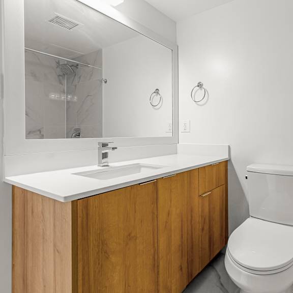 a white bathroom with a wooden vanity and a white toilet.