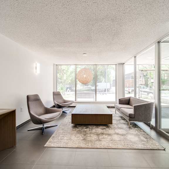 a living room with a brown sofa, grey armchair, and a coffee table.