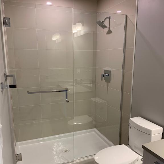 a bathroom with a toilet, shower, and glass tiles.