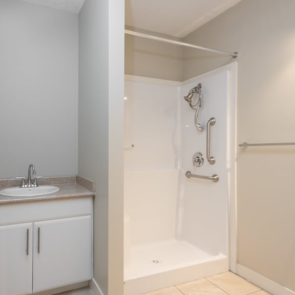 a white bathroom with a sink and a shower.