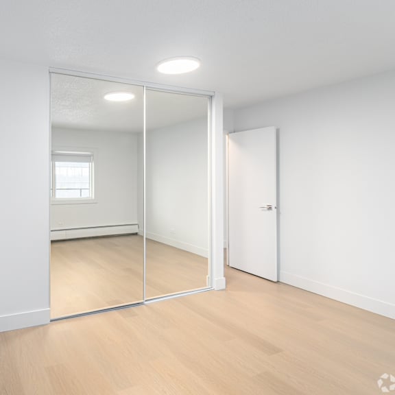 a room with a mirror on the wall and wooden flooring.