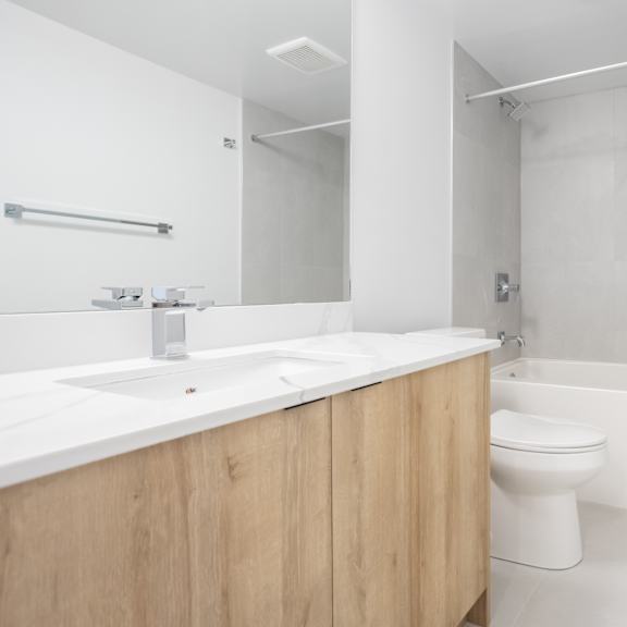 a white bathroom with a wooden vanity and a white toilet.
