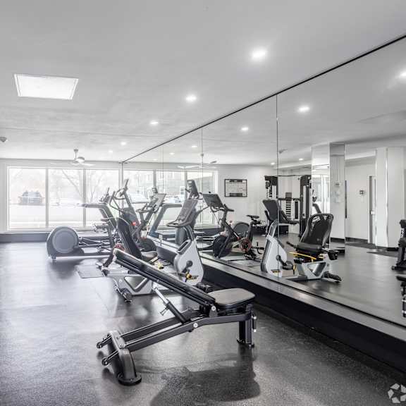 a gym with a variety of equipment including treadmills, weights, and exercise machines.