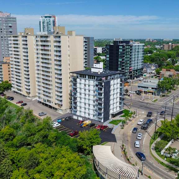a cityscape with a mix of residential and commercial buildings, surrounded by greenery and roads with vehicles.