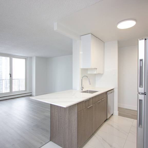 a kitchen with a white counter top and a refrigerator.