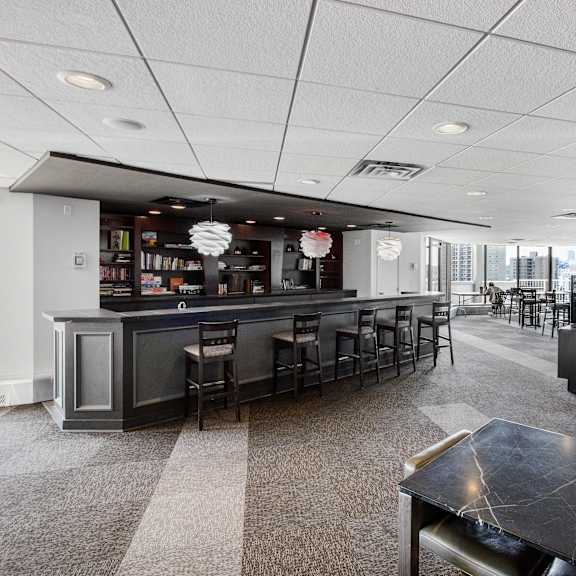 a black and white image of a room with a bar and chairs.