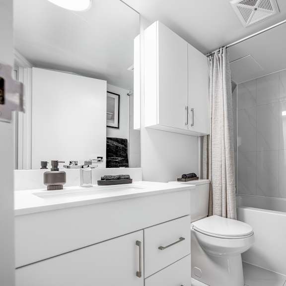 a white bathroom with a toilet, sink, and shower.