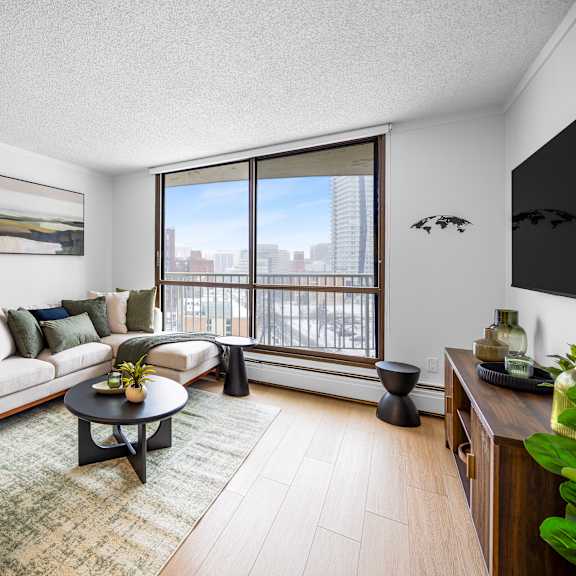 a living room with a couch, a chair, a coffee table, and a large window.