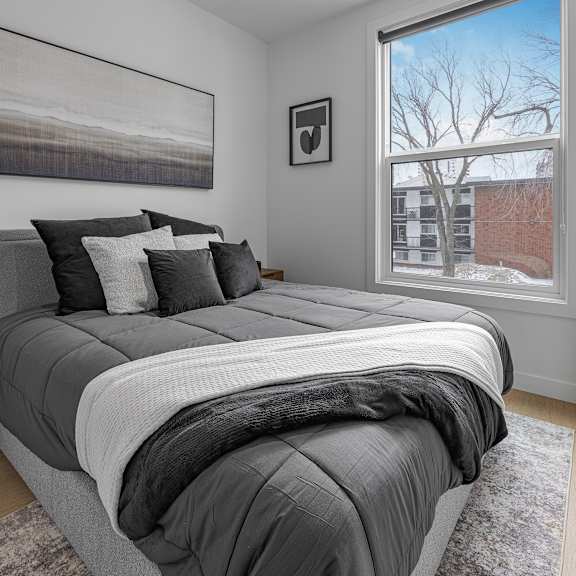 a bedroom with a large bed and a window showing a building outside.