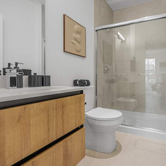 a modern bathroom with a toilet, sink, and shower.