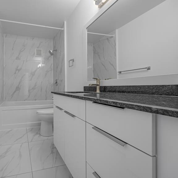 a white bathroom with a marble shower and toilet.