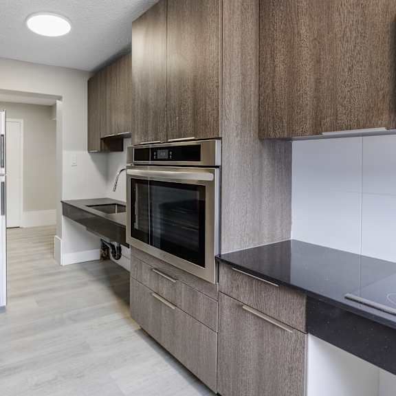 a modern kitchen with dark wood cabinets and stainless steel appliances.