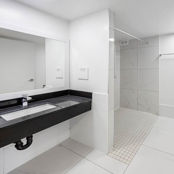 a white bathroom with a toilet, sink, and shower.
