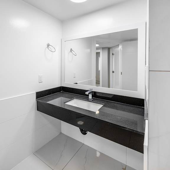 a white bathroom with a sink and mirror.