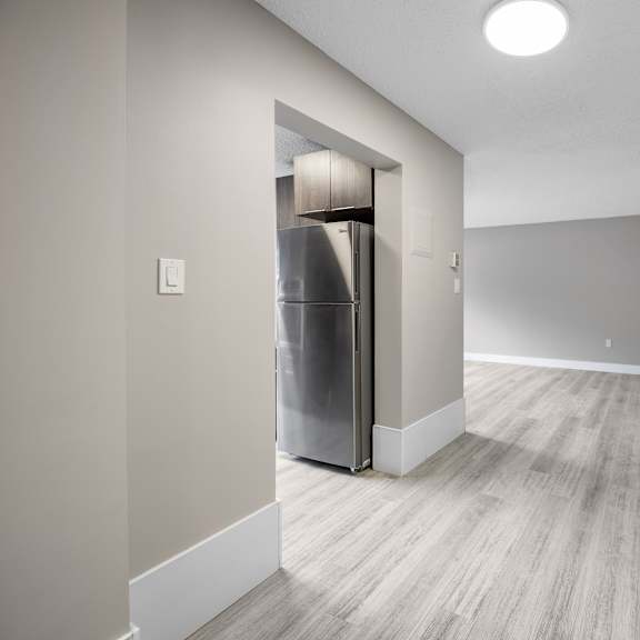 a kitchen with a refrigerator and a door on the left.