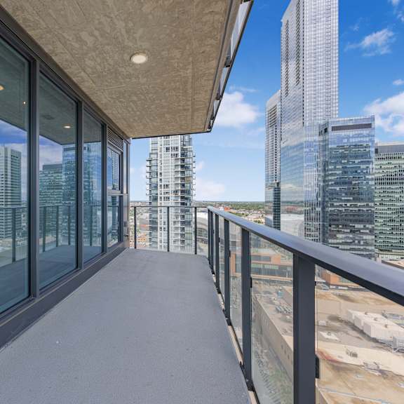 a balcony with glass doors overlooks a cityscape.