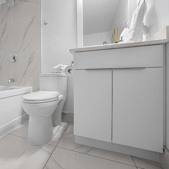 a white bathroom with a toilet, sink, and bathtub.