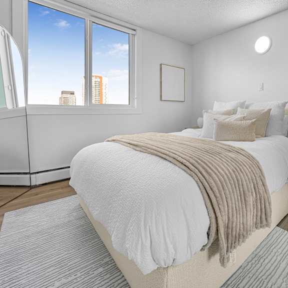 a bedroom with a large bed and a window overlooking the city.