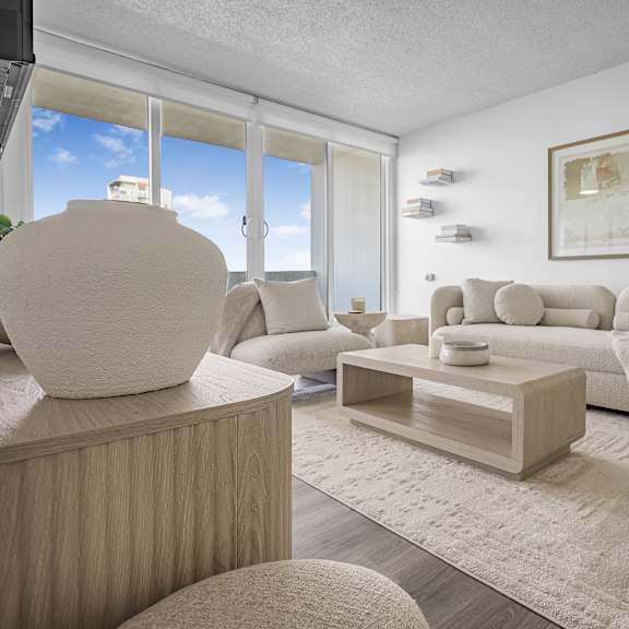 a modern living room with a large sofa, a coffee table, and a large sculpture on a wooden cabinet.
