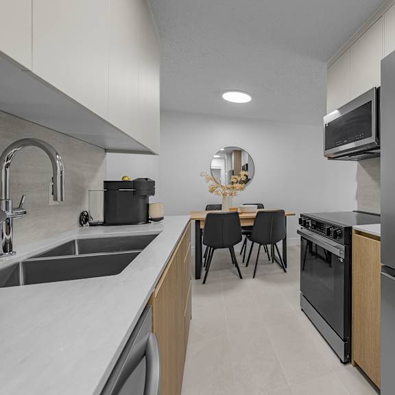 a modern kitchen with a stainless steel refrigerator, sink, and dining table.
