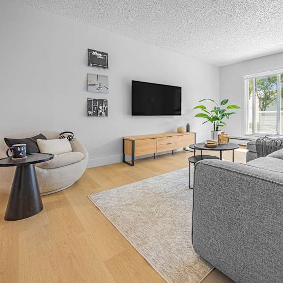 a living room with a grey couch, a black table, and a television.