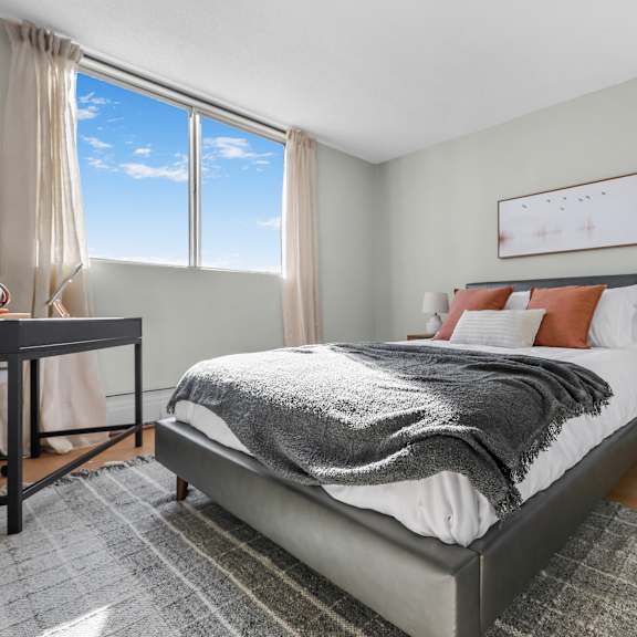 a bedroom with a large bed and a window overlooking the sky.