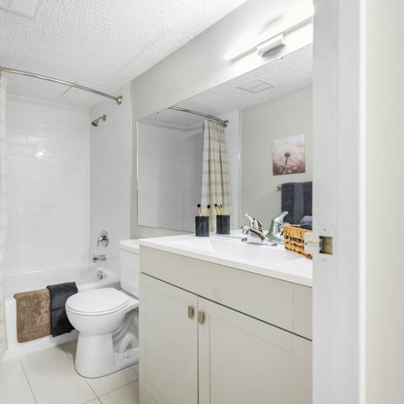 a white bathroom with a toilet, sink, and shower curtain.