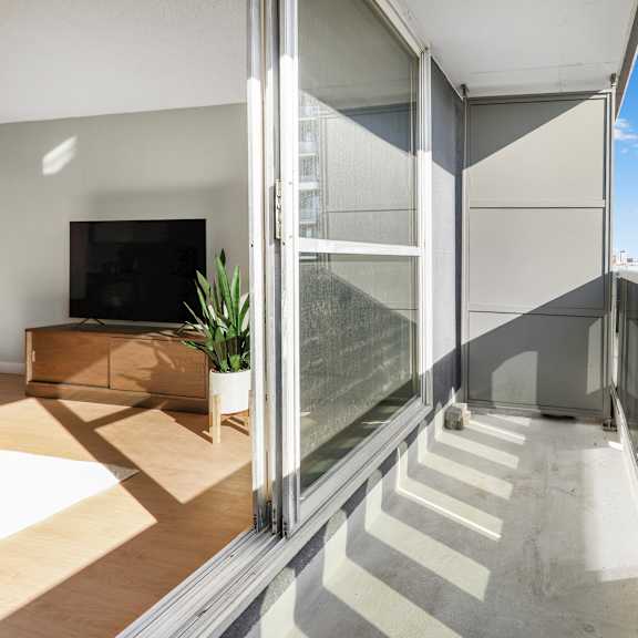 a modern balcony with glass railings and a flat screen tv in the living room.