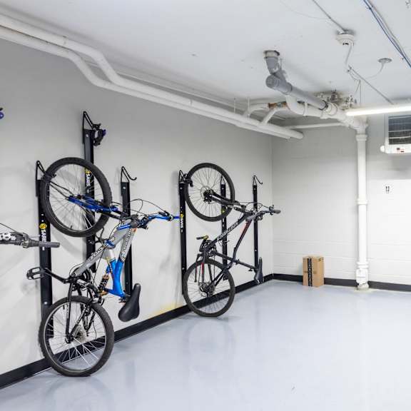 a room with a white floor and walls, containing a bicycle rack with several bicycles and a white door.