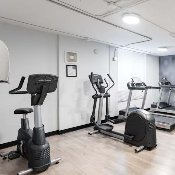 a gym with a variety of exercise equipment including treadmills, stationary bikes, and elliptical machines.
