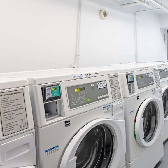a row of industrial washing machines in a laundry room.