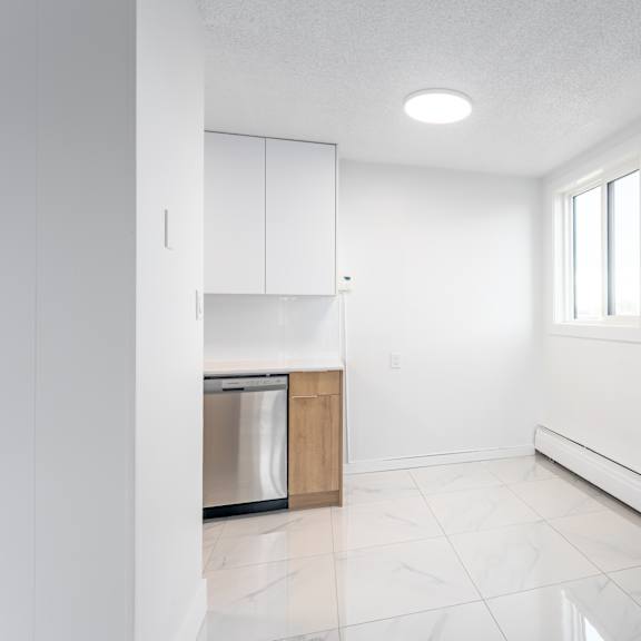 a white kitchen with a dishwasher and a window.