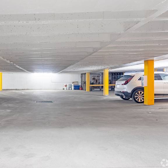 a parking garage with cars parked and yellow poles.