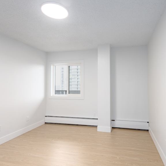 a white room with a window and wooden flooring.