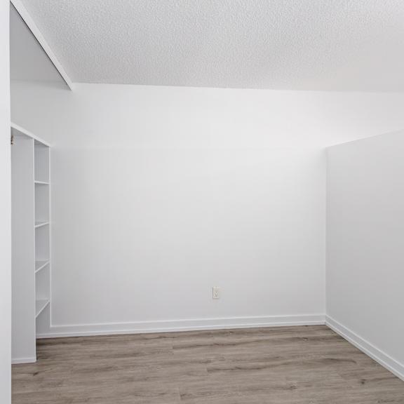 a white room with a wooden floor and a white wall with a switch.